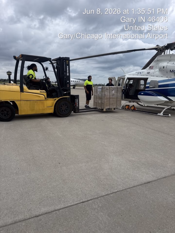 A forklift carrying a pallet across the apron toward a waiting aircraft at Gary/Chicago International Airport